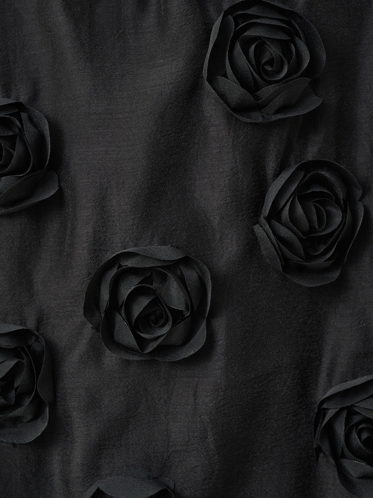 Black fabric adorned with evenly spaced black fabric roses arranged in a subtle pattern.