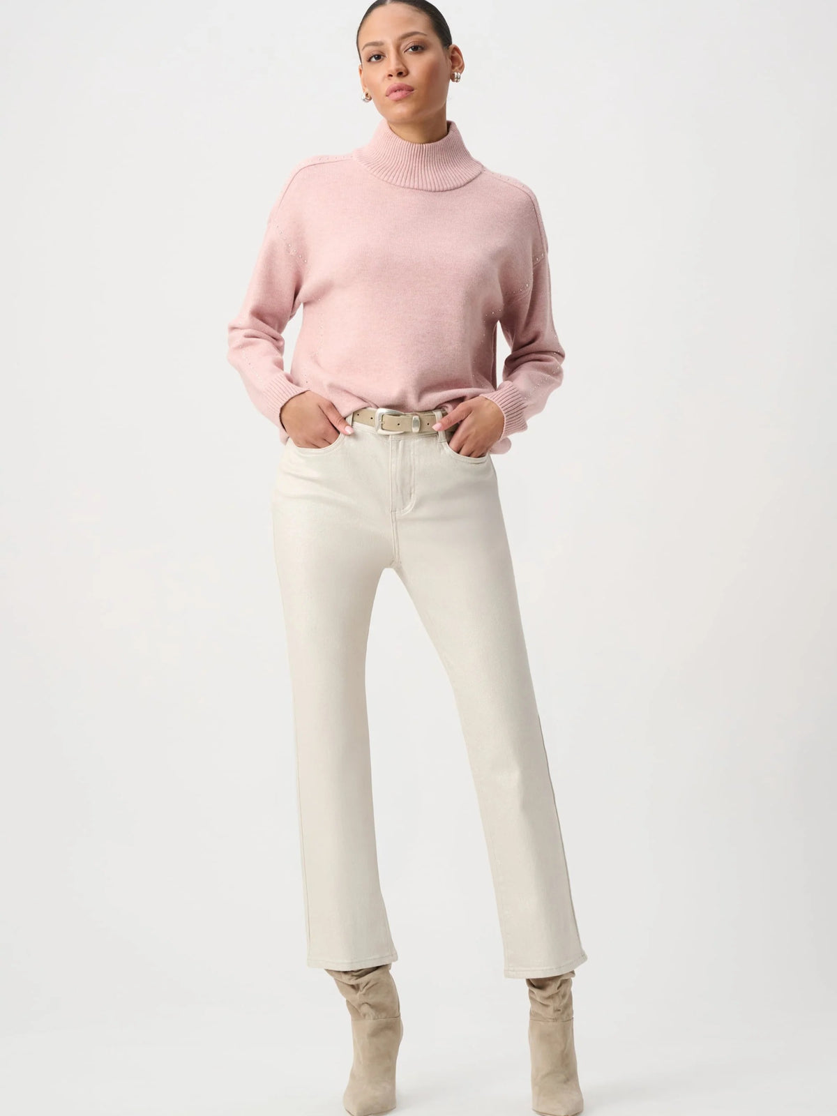 Light pink turtleneck sweater paired with off-white high-waisted pants and beige ankle boots against white background.