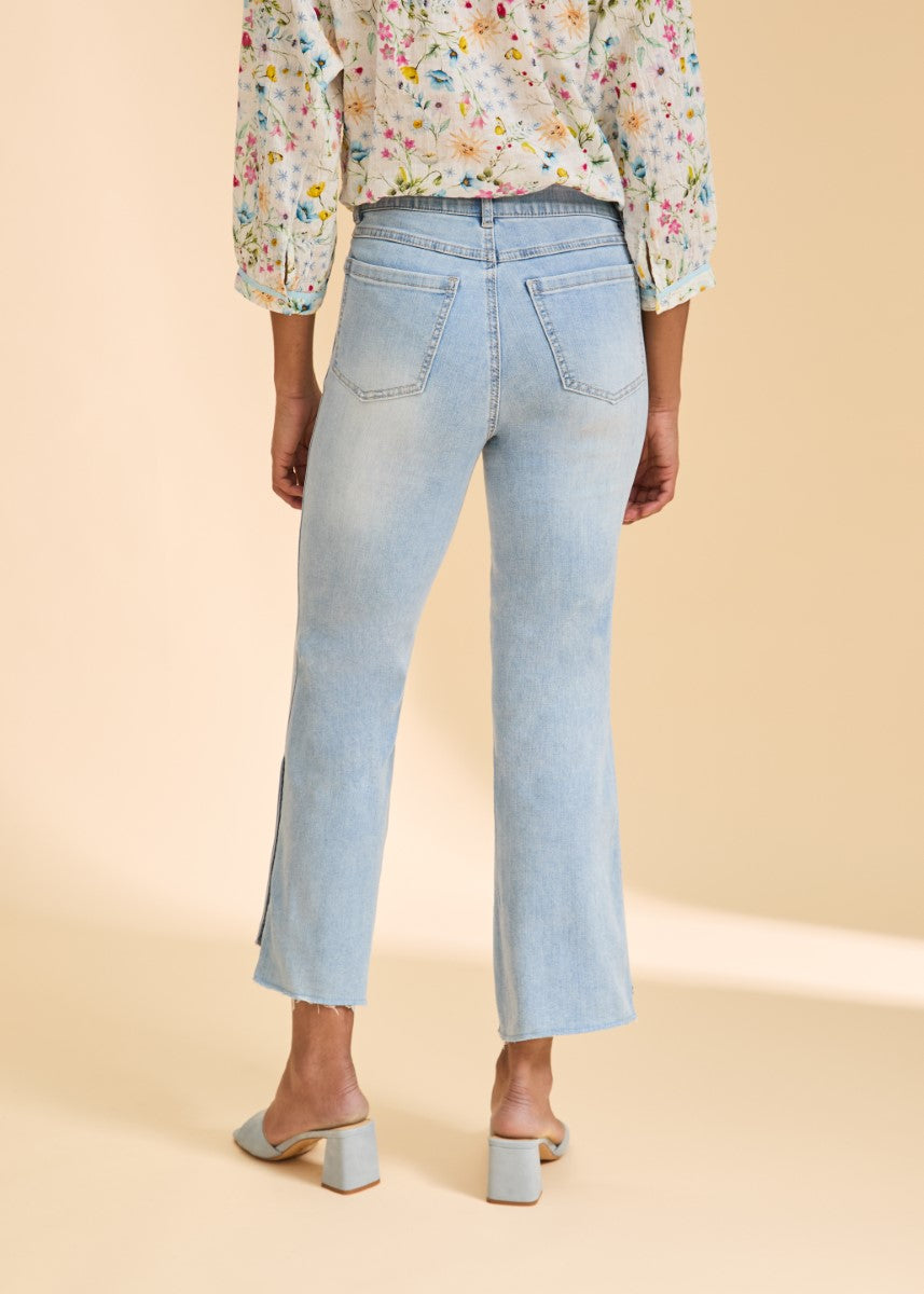 Light wash denim jeans with a slight flare and raw hem, paired with a floral print long sleeve top