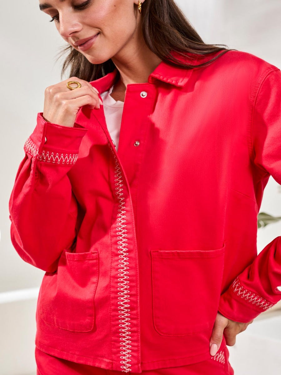 Close-up of bright red Tribal Playful Embroidered Detail Denim Jacket by Tribal Sportswear Inc. with contrast stitching on cuffs and front