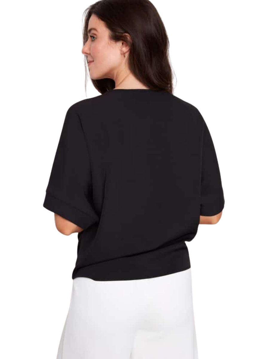 Back view of a black short-sleeve top paired with white bottoms against a plain background.