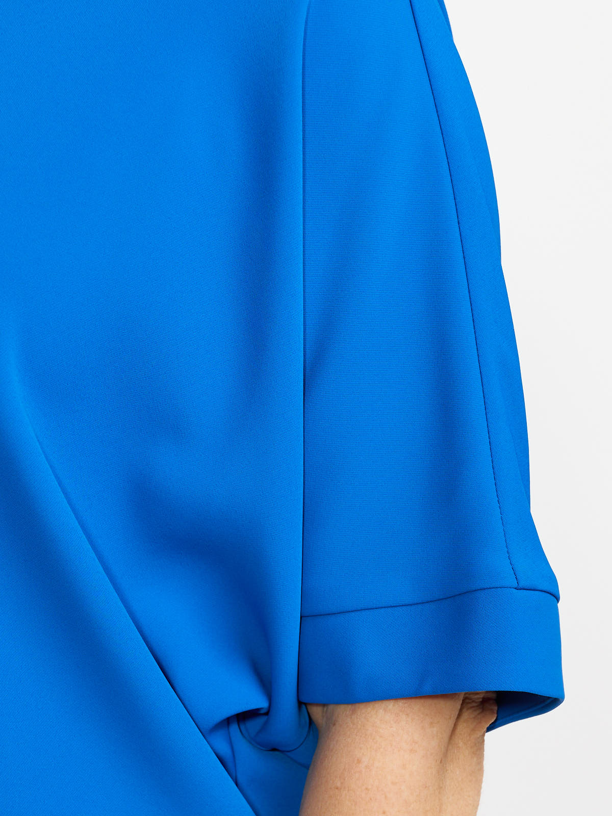 Close-up of a bright blue short sleeve garment with smooth fabric and a folded cuff detail.