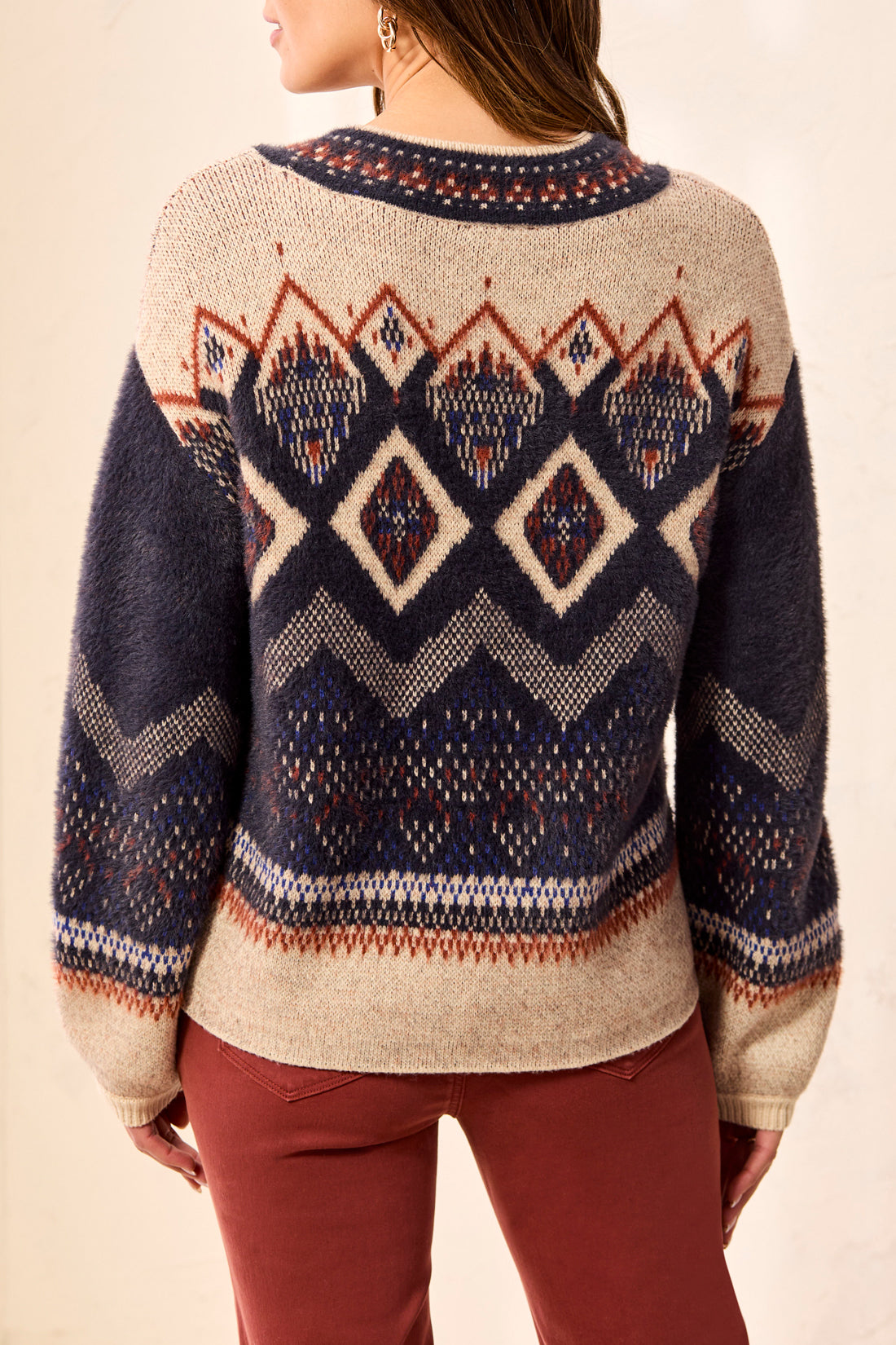 Back view of a knitted sweater with geometric patterns in navy blue, beige, and rust colors