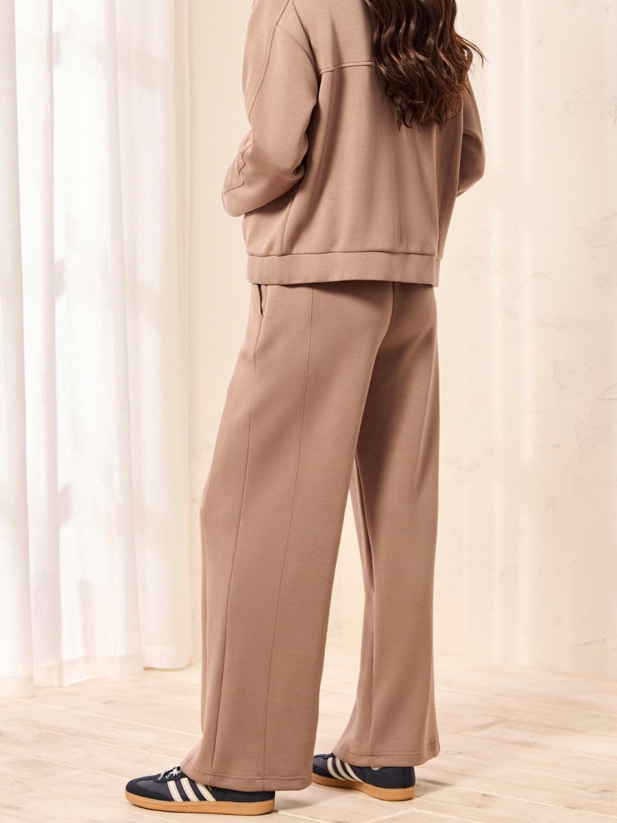 Light brown wide-leg pants paired with a matching top and dark blue sneakers with white stripes.
