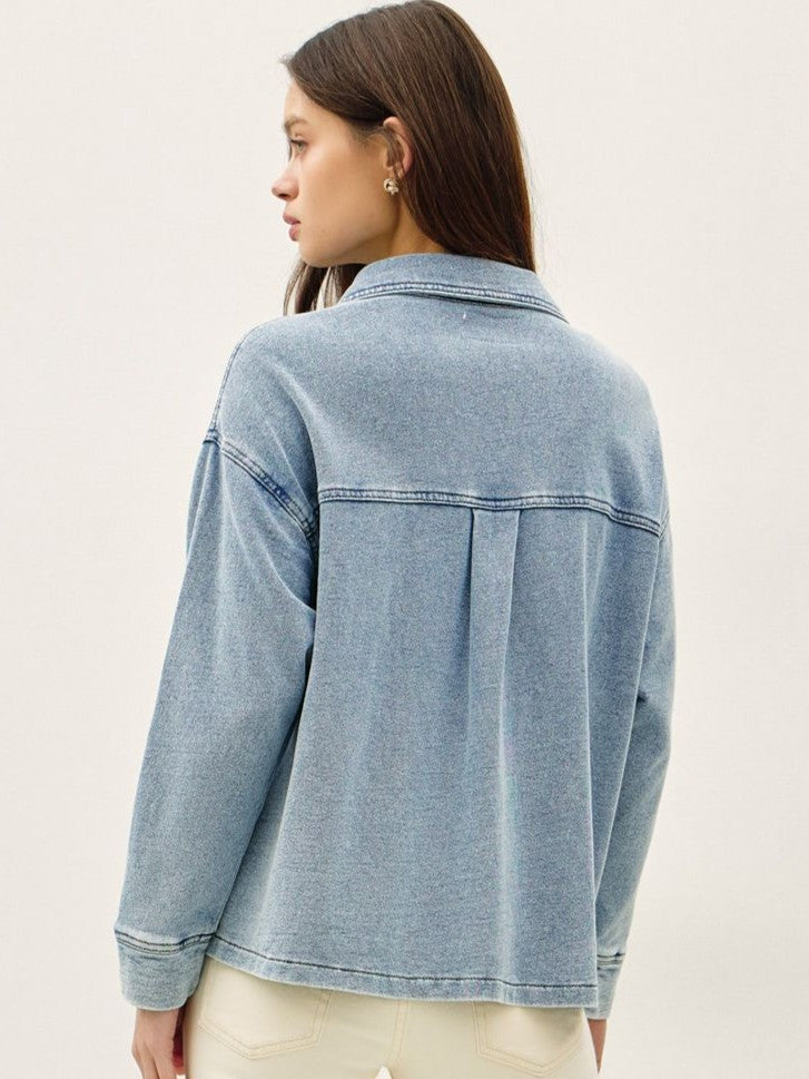 Light blue denim jacket with a relaxed fit, long sleeves, and a back pleat detail shown from behind