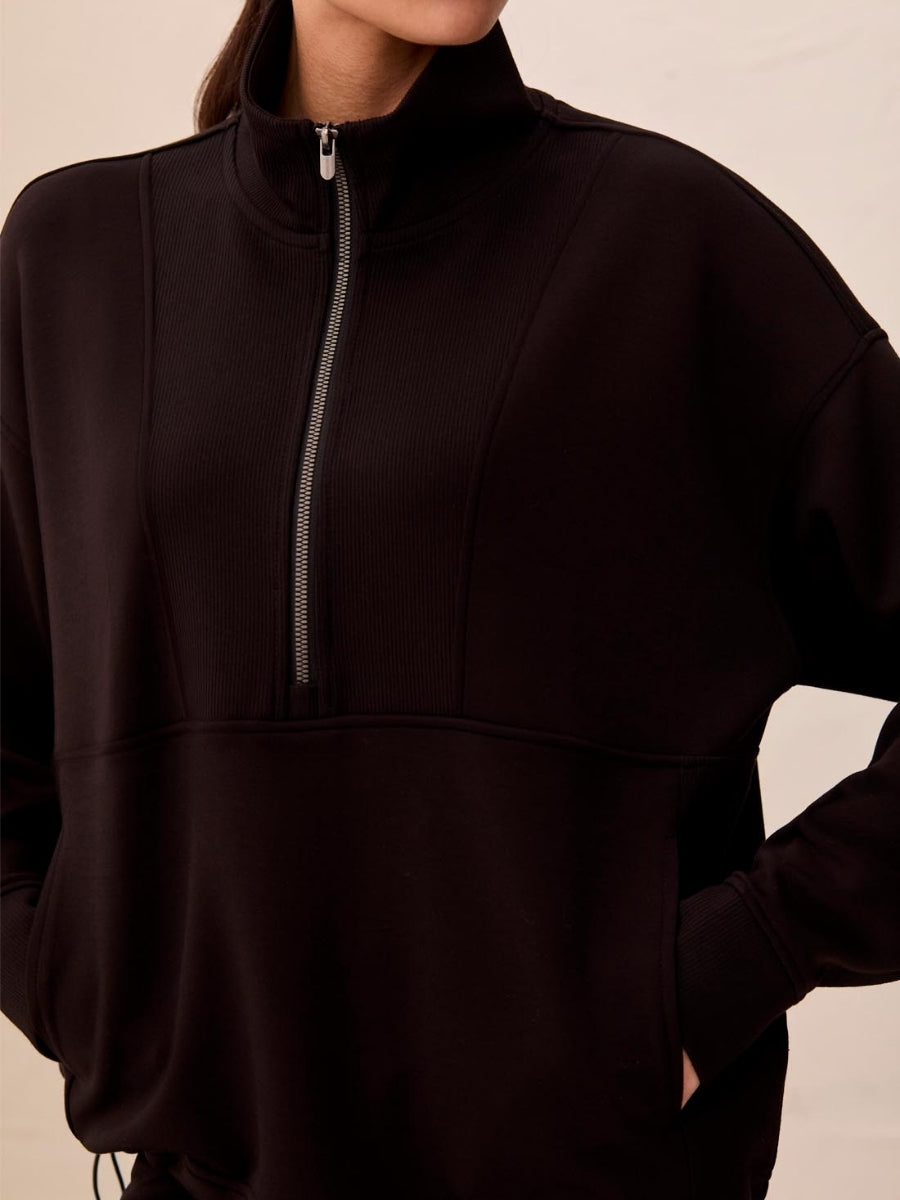 Black half-zip pullover sweater with ribbed detailing and a high collar on a neutral background.
