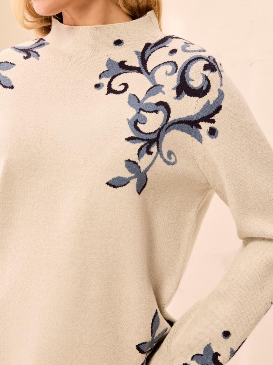 Cream-colored sweater with blue and black floral embroidery on shoulder and sleeve edges
