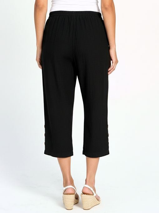 Back view of black cropped wide-leg pants with elastic waistband, worn with white wedge sandals and white top.