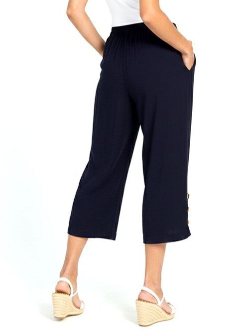 Navy wide-leg cropped pants with side buttons and elastic waistband paired with white wedge sandals