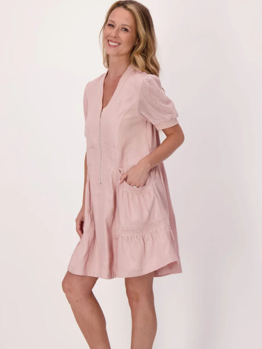 Light pink short dress with puff sleeves, front zipper, and gathered pockets worn by a smiling figure on a plain background.