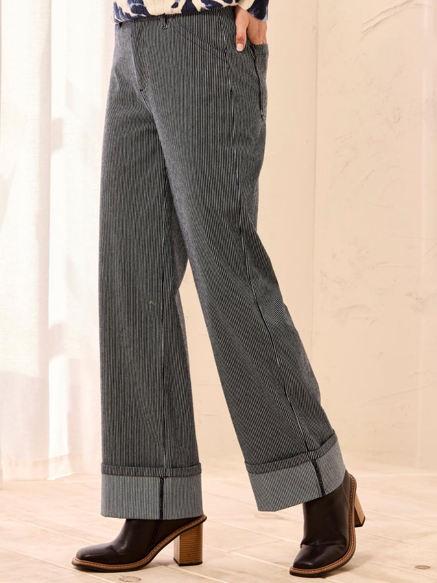 Pinstriped wide-leg pants with cuffed hems paired with black leather ankle boots featuring wooden heels