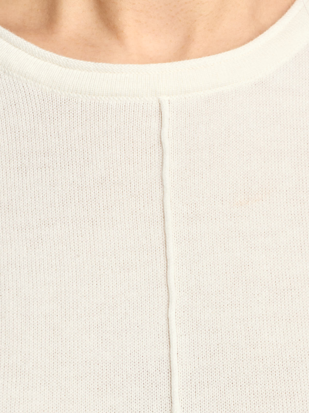 Close-up of a cream knit sweater with a round neckline and a vertical seam detail down the center front