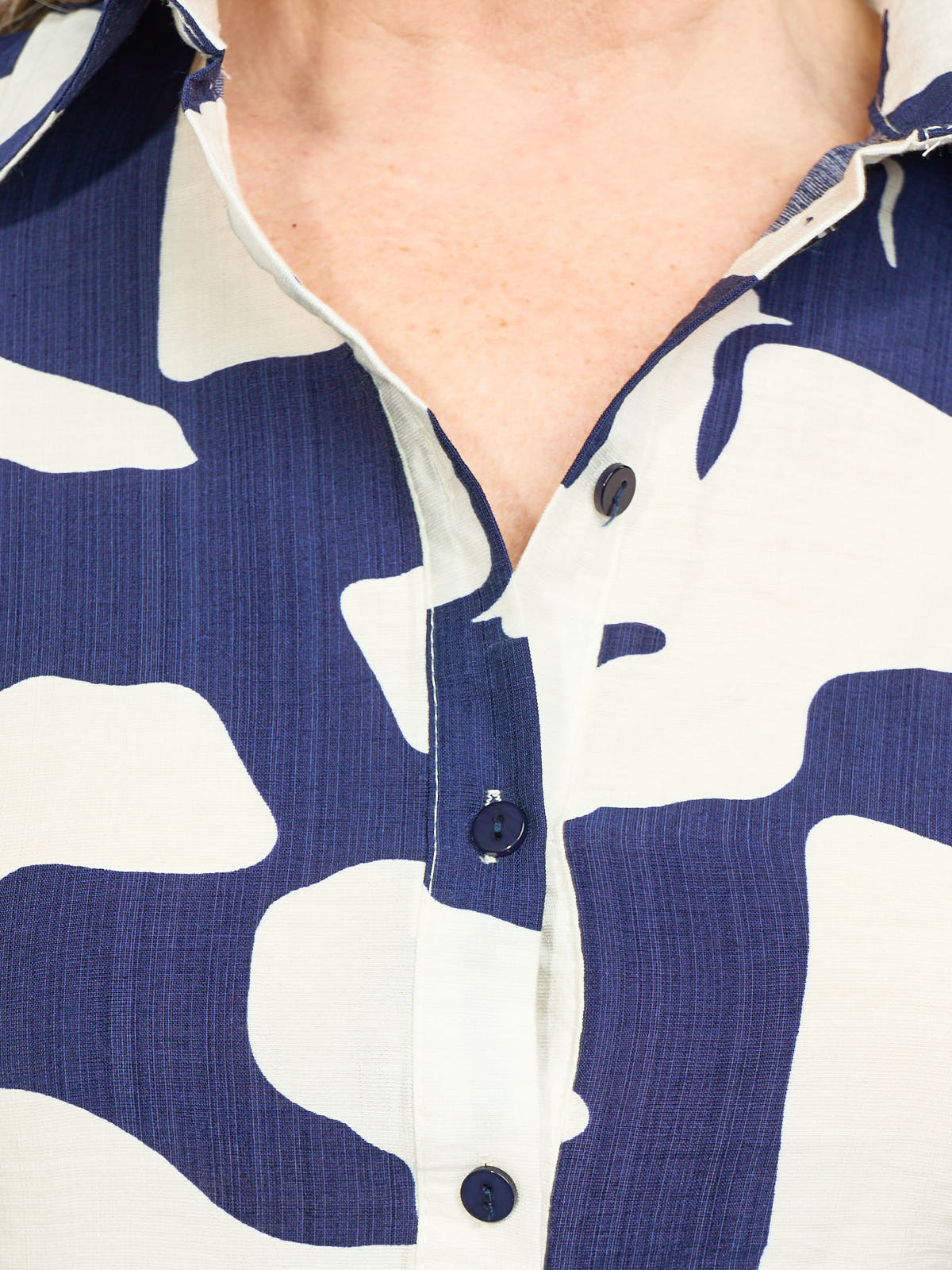 Close-up of a blue and white patterned fabric shirt with black buttons along the front placket.