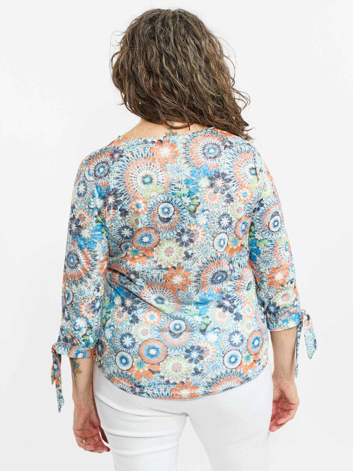 Multicolored abstract floral patterned top with three-quarter sleeves and tied cuffs on a white background.