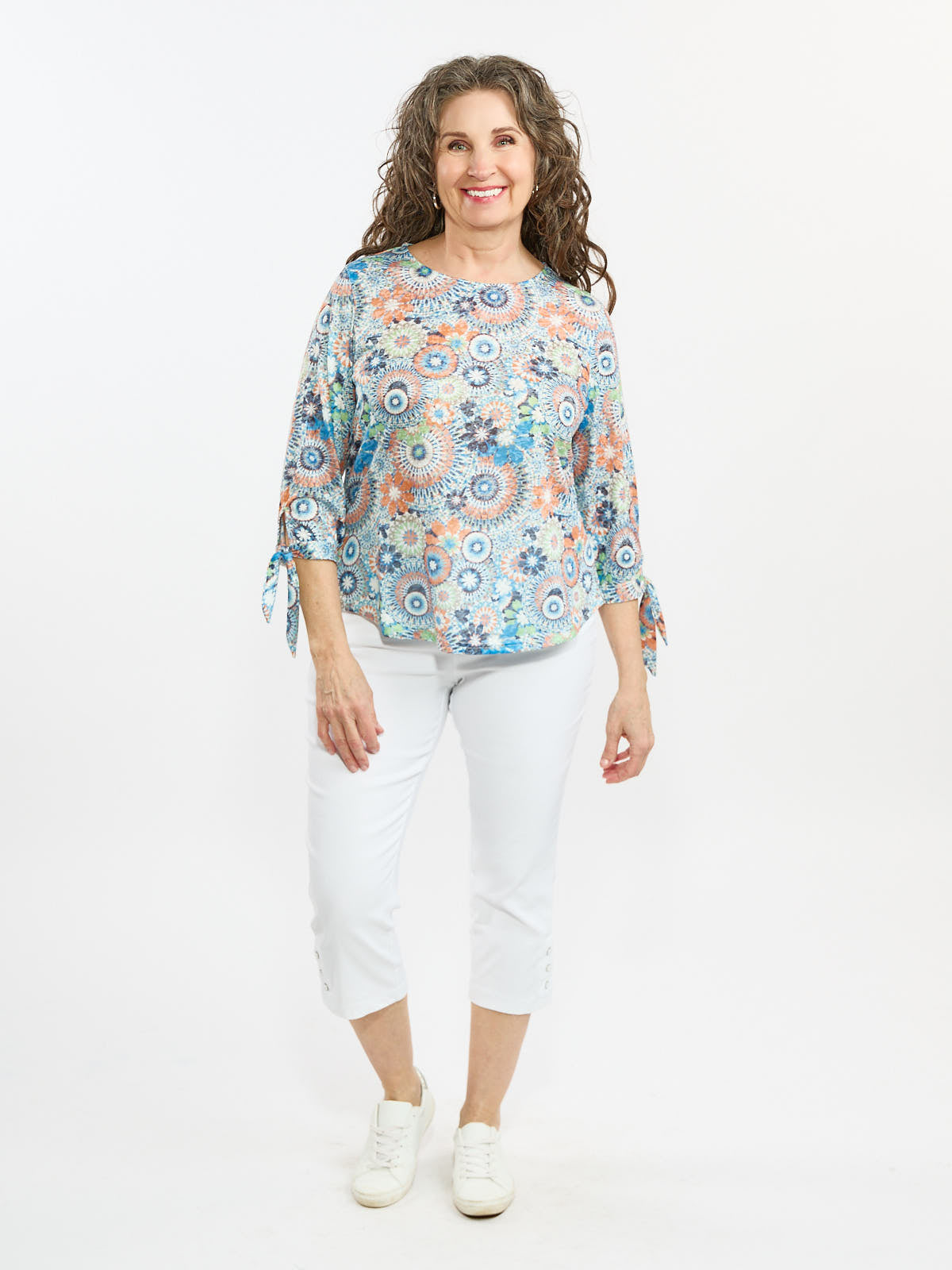 Light blue floral patterned top with three-quarter sleeves paired with white cropped pants and white sneakers.