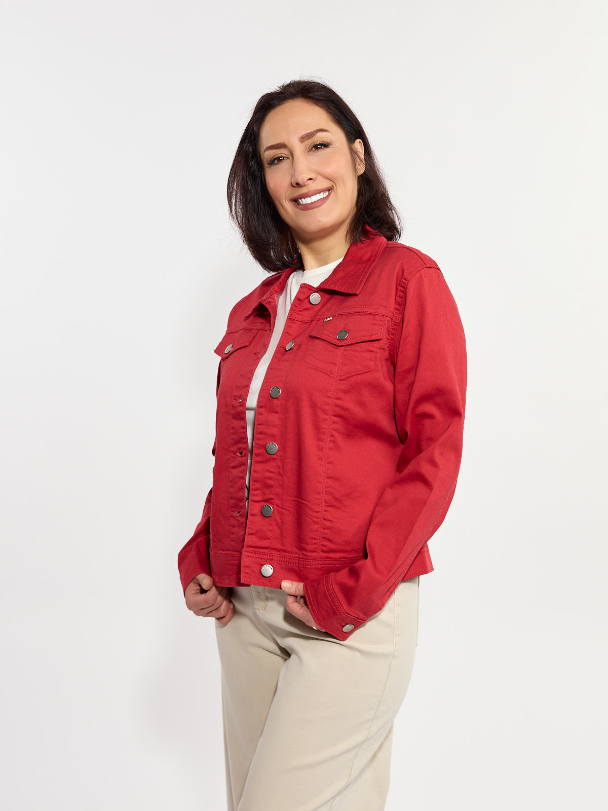 Red button-up denim jacket with front pockets paired with light beige pants on a smiling figure