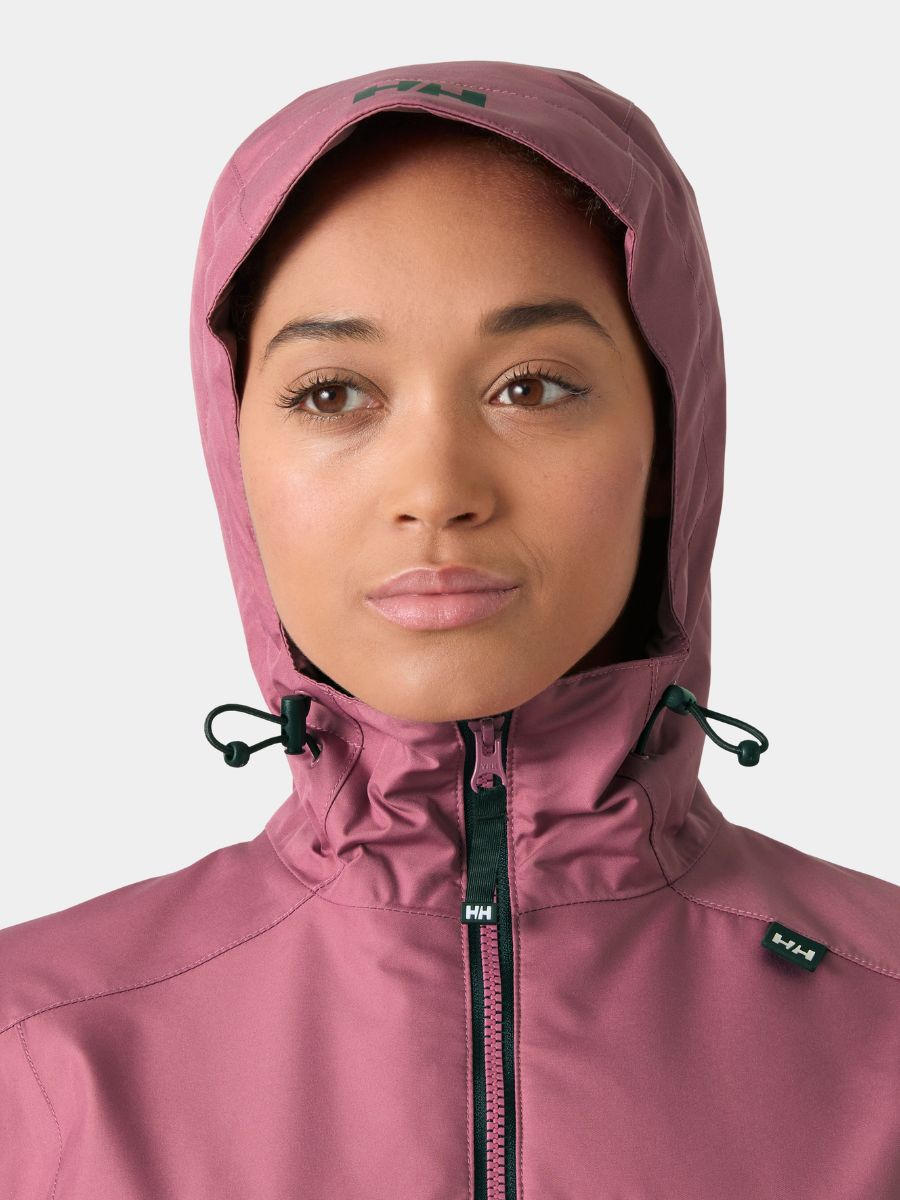 Close-up of a face partially covered by a mauve hooded jacket with black drawstrings and zipper details