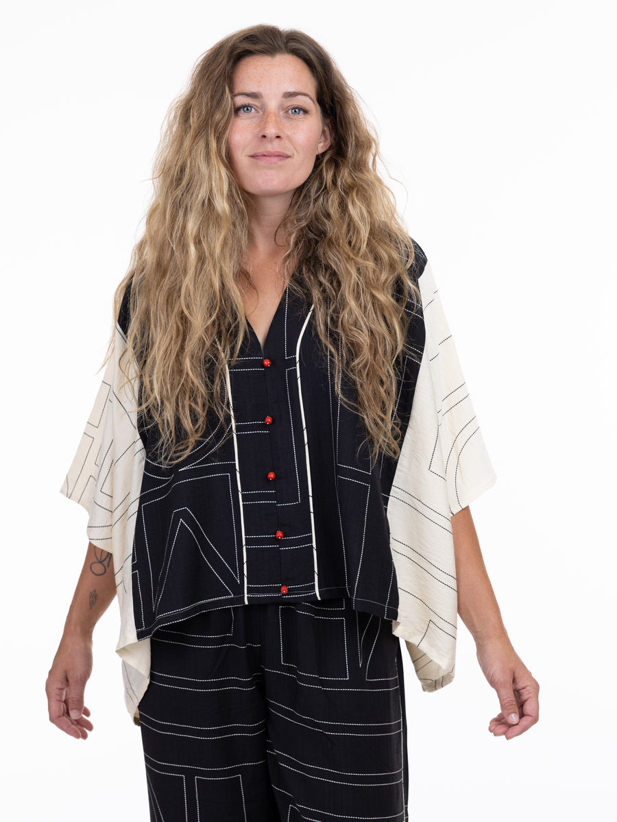 Loose black and cream patterned top with red buttons paired with matching black trousers with geometric lines