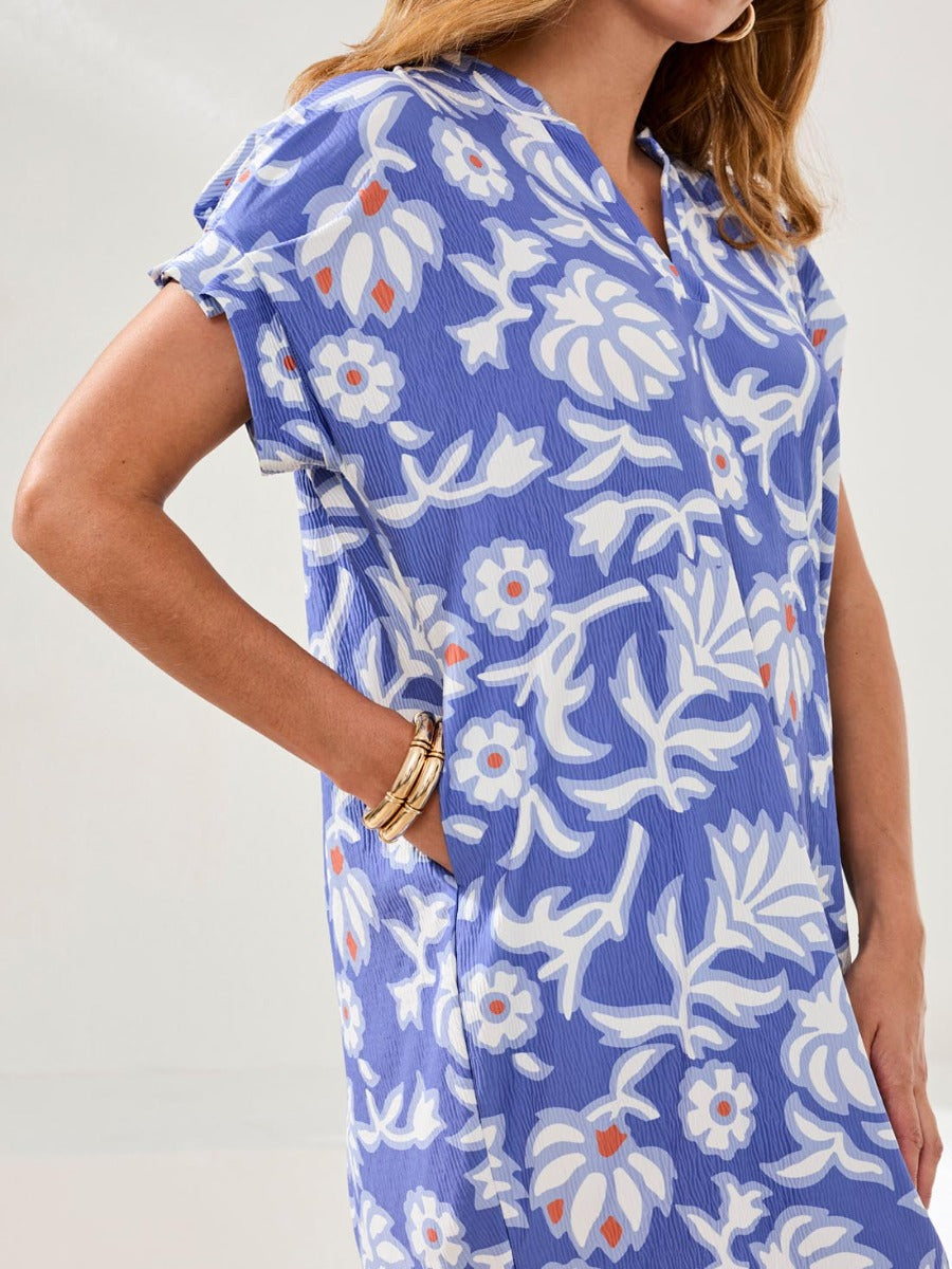 Blue floral patterned short sleeve dress with pockets and gold bracelets on the wrist