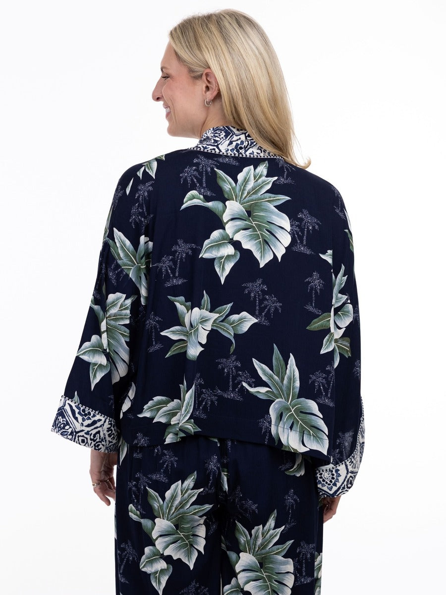 Back view of a person wearing a navy floral patterned jacket and matching pants with light green leaves and white accents