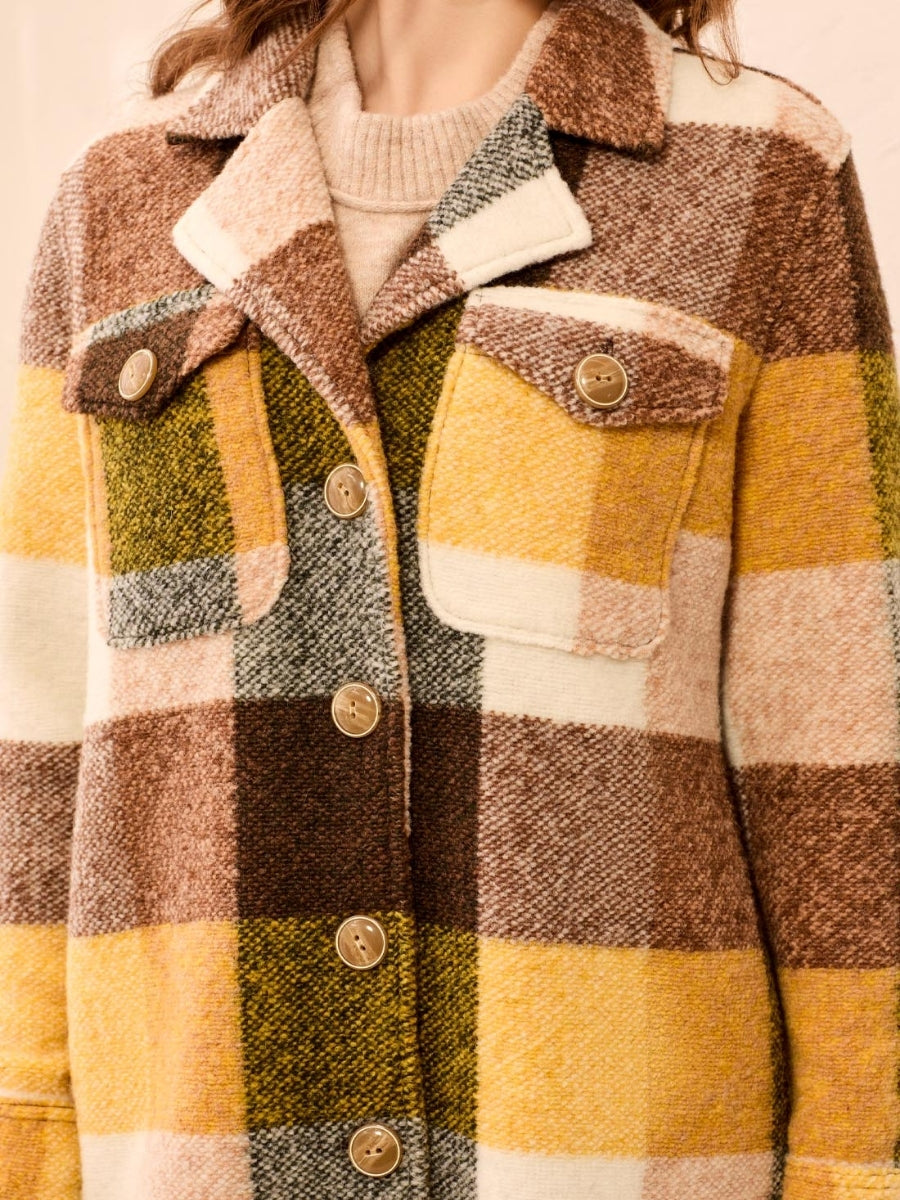 Close-up of a textured wool plaid jacket with front pockets and buttons in autumnal colors.