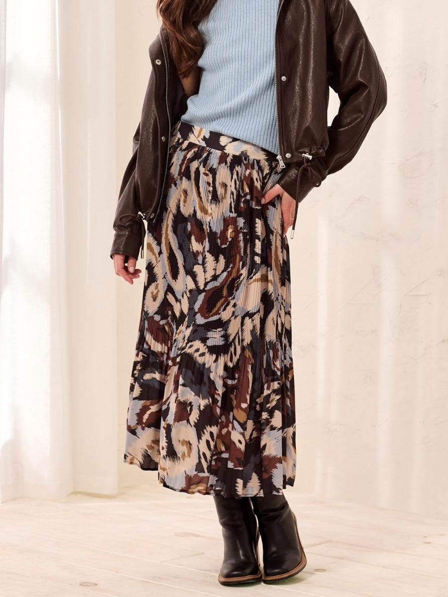 Pleated midi skirt with abstract animal print paired with light blue ribbed top, brown jacket, and black boots.