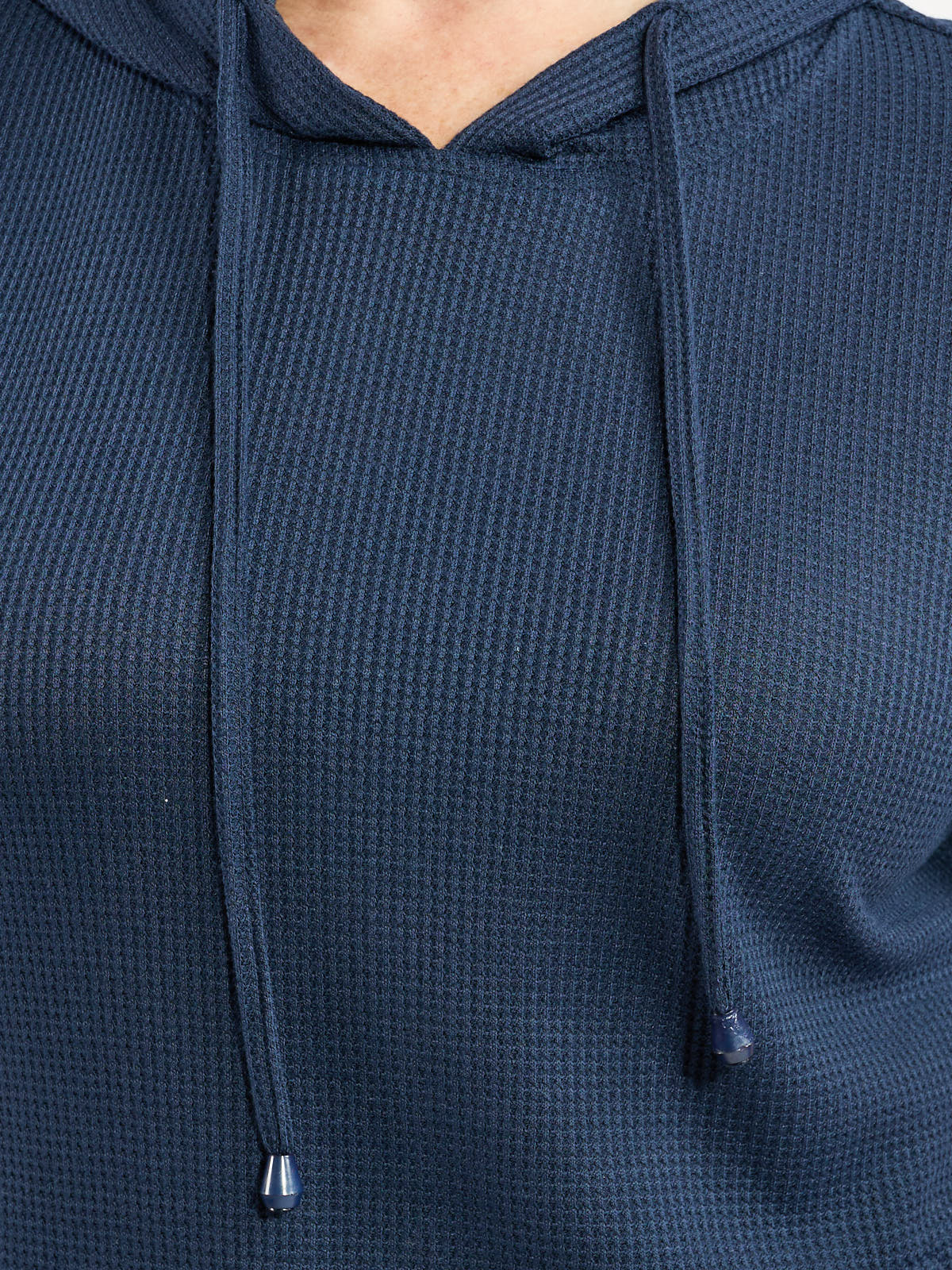 Close-up of a navy blue textured knit hoodie with drawstrings and a V-shaped neckline detail.