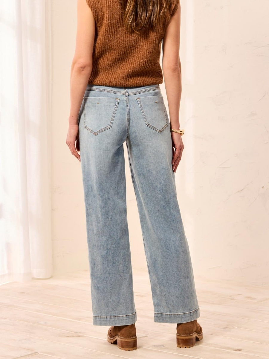 Light blue denim jeans with a wide-leg fit paired with brown suede ankle boots and a sleeveless knit top.