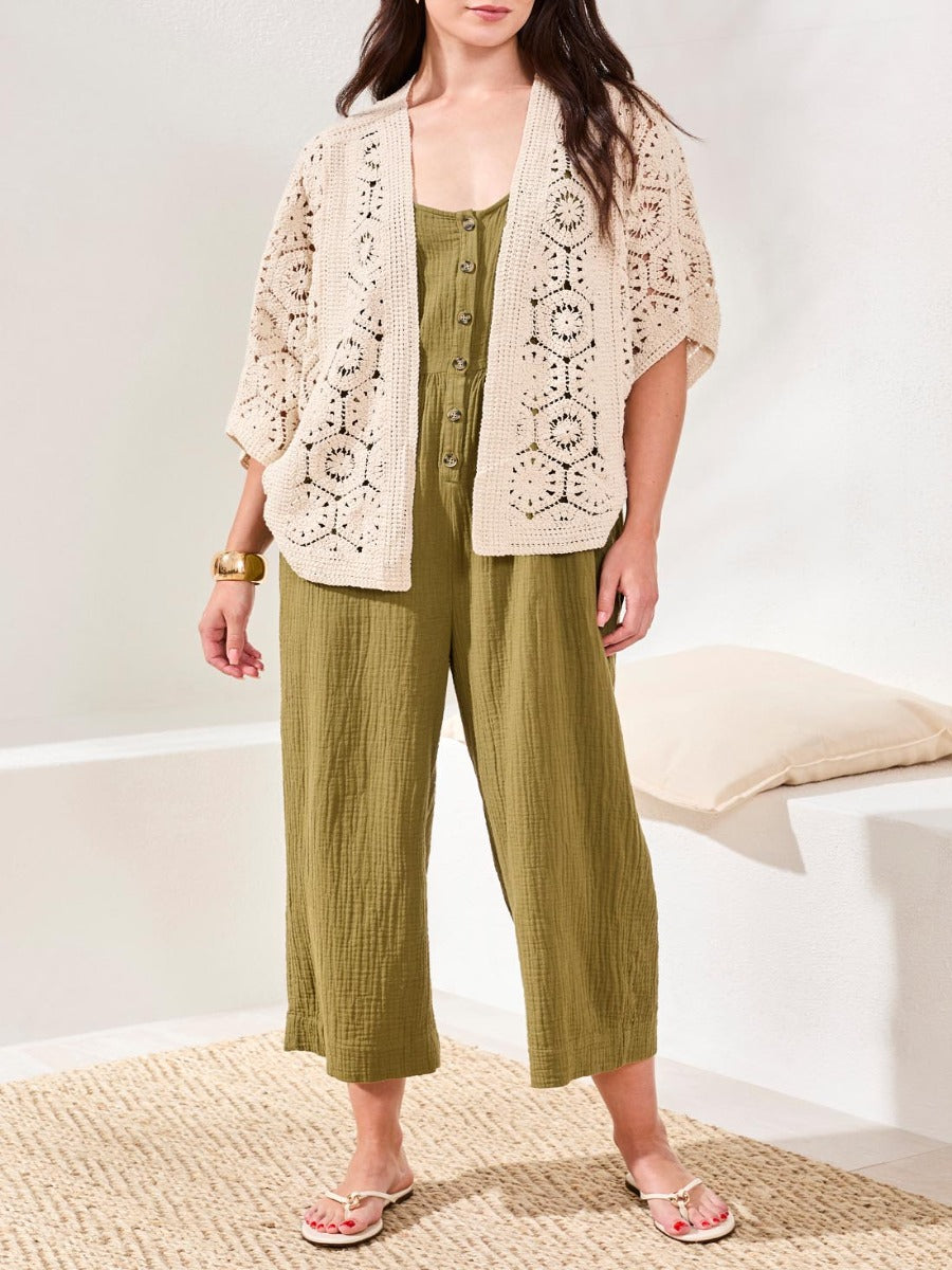 Open-knit beige cardigan over sleeveless olive green button-up wide-leg jumpsuit with sandals and bracelet