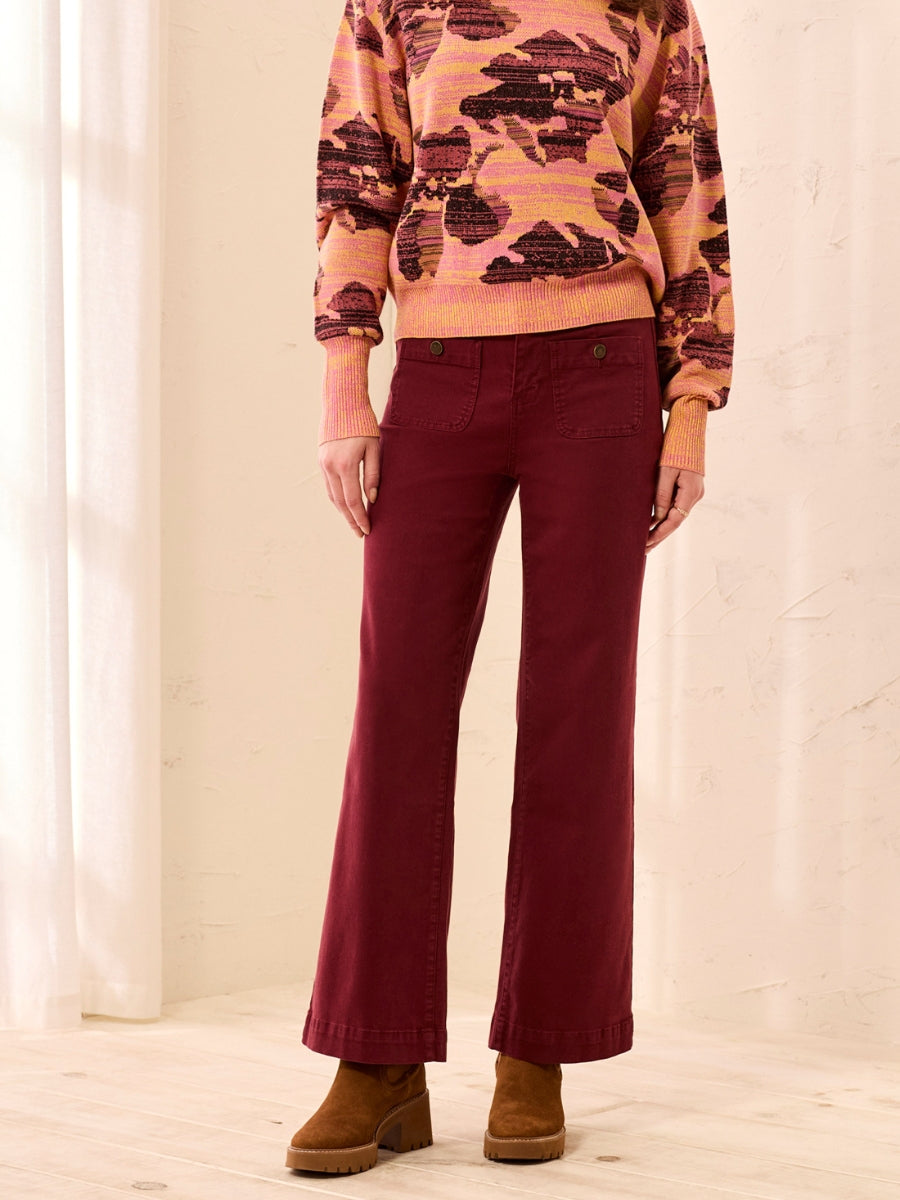 Rust-colored wide-leg pants paired with a patterned knit sweater and brown suede ankle boots.