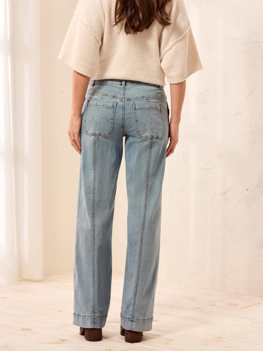 Light blue denim jeans with back pockets and visible seam detailing, paired with a cream knit top.