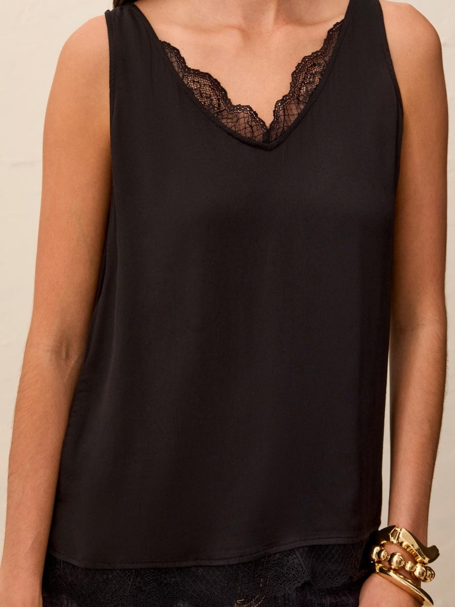 Black sleeveless top with lace trim at the V-neckline paired with a gold-tone bracelet on the wrist.