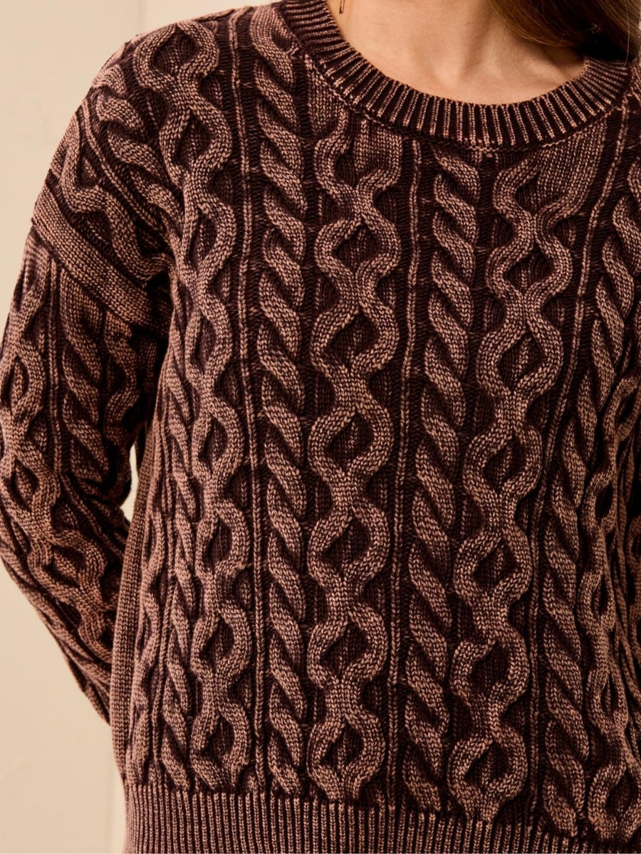 Close-up of a brown textured cable-knit sweater with a ribbed neckline and hem.