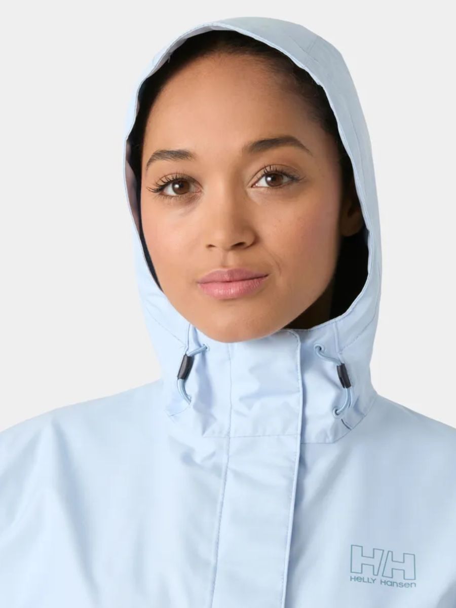 Person wearing a light blue hooded jacket with Helly Hansen logo on a white background