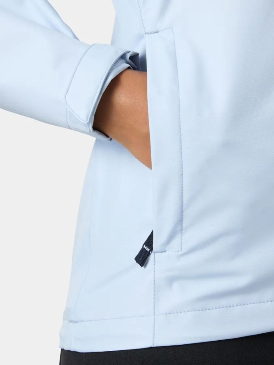 Light blue jacket sleeve and side pocket with a hand partially inserted, visible black tag detail.