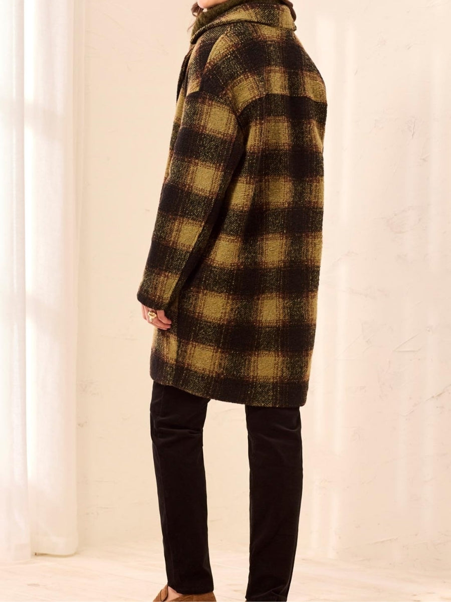 Brown and black plaid wool coat with a mid-thigh length, worn over black pants in a neutral setting.