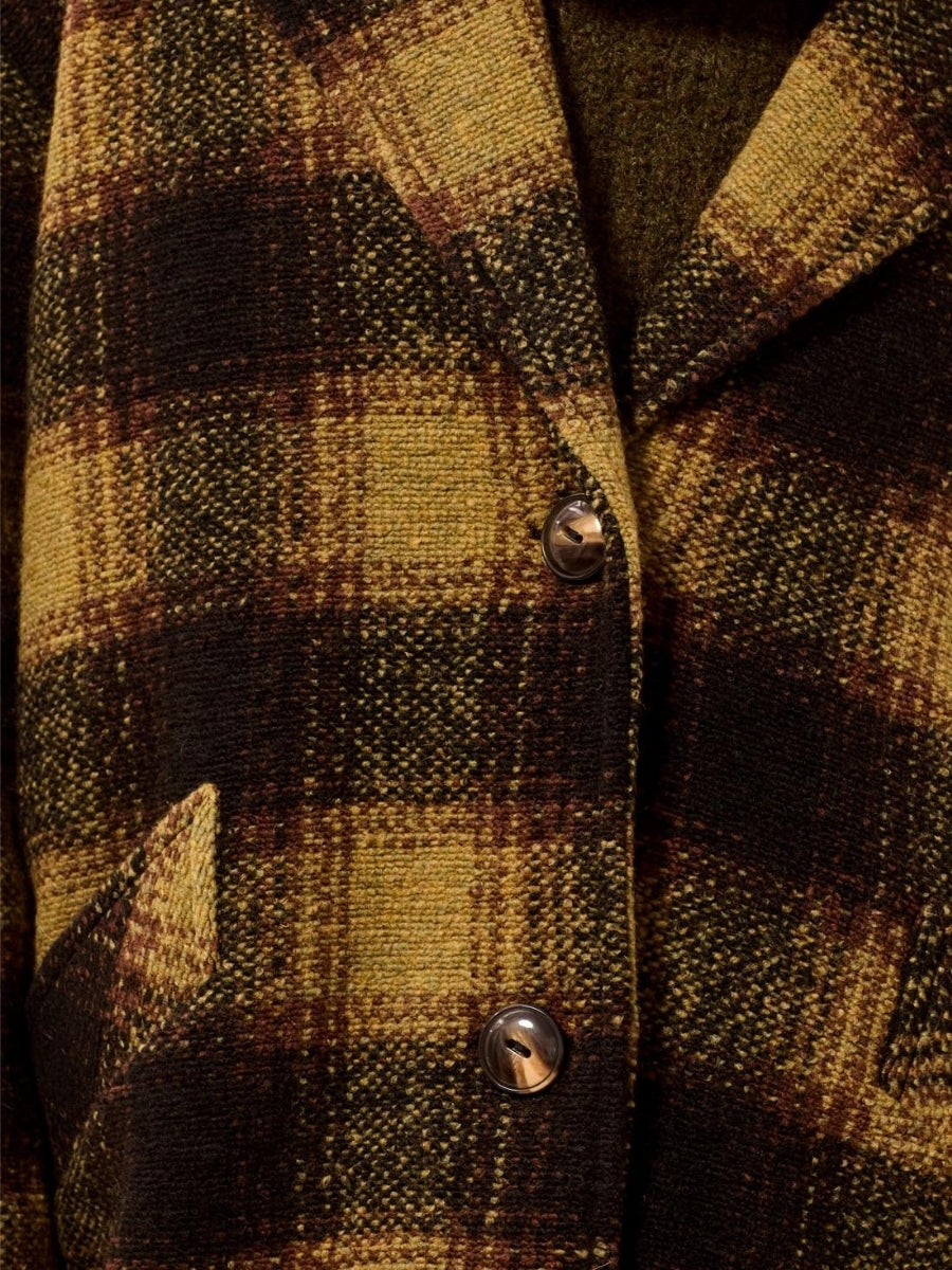 Close-up of a brown and yellow plaid textured wool coat with buttons and a front pocket detail.