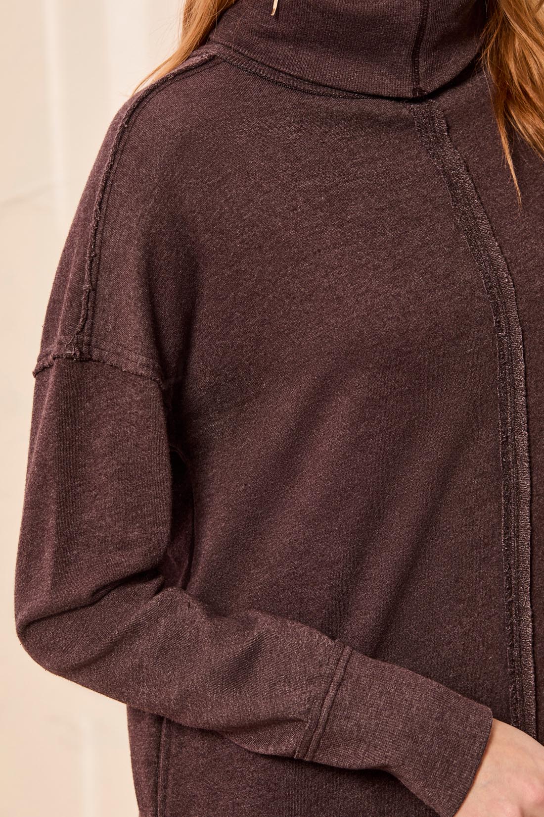 Close-up of a dark brown long-sleeve sweater with visible seam detailing and a high collar.