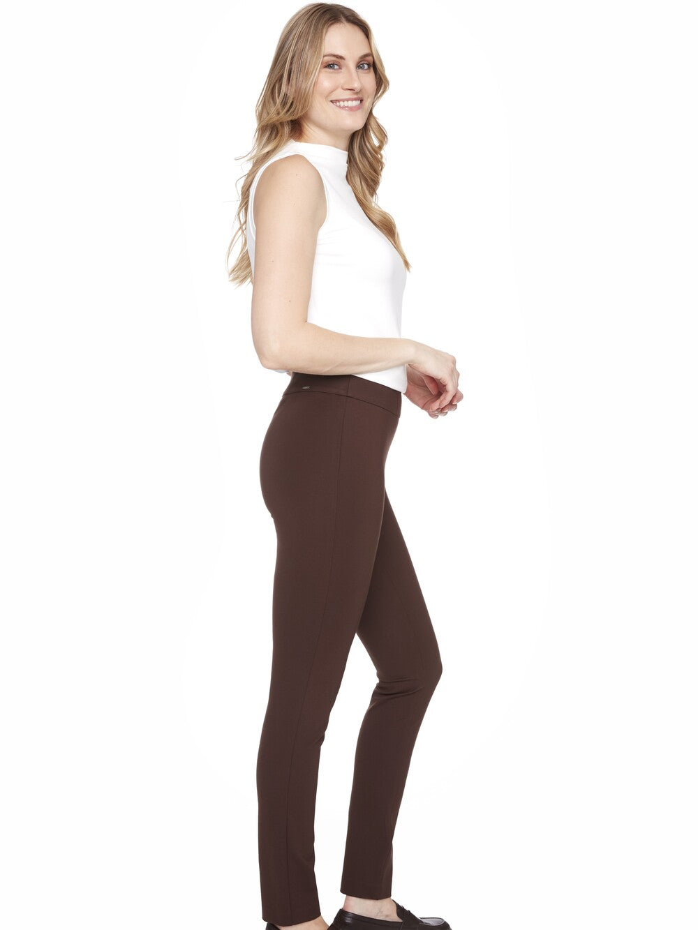 Model in a white sleeveless top wearing UP Ponte Basic Slim Pant 31" in brown by Up, styled simply
