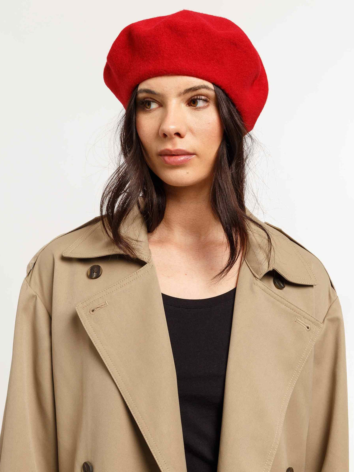 Woman in a red beret and beige trench coat over a black top