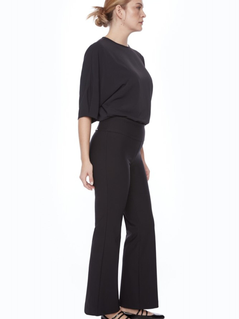 Side view of a model wearing black UP Precision Ponte Slim Boot 31" Pant by Up with a simple black top.