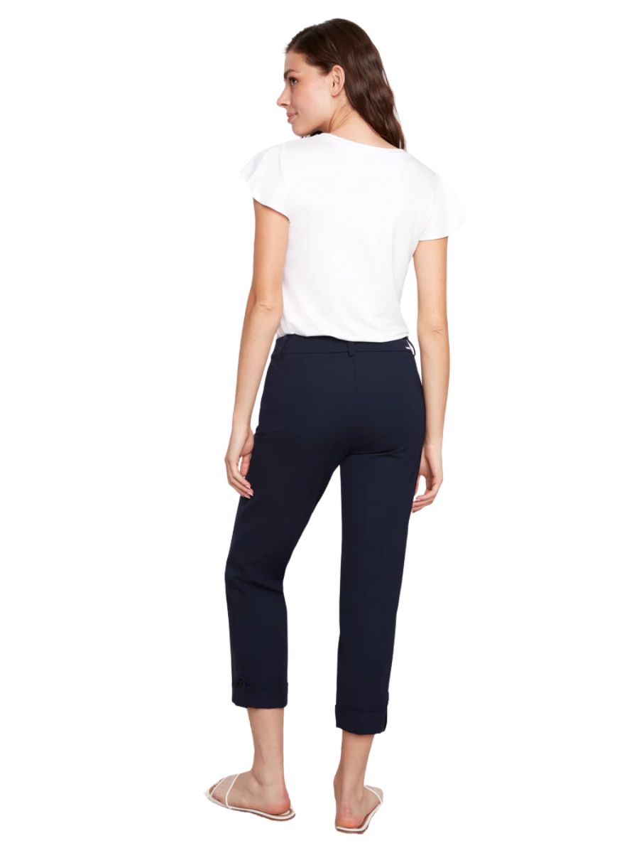 Person standing facing away wearing a white short sleeve top and navy cropped pants with sandals