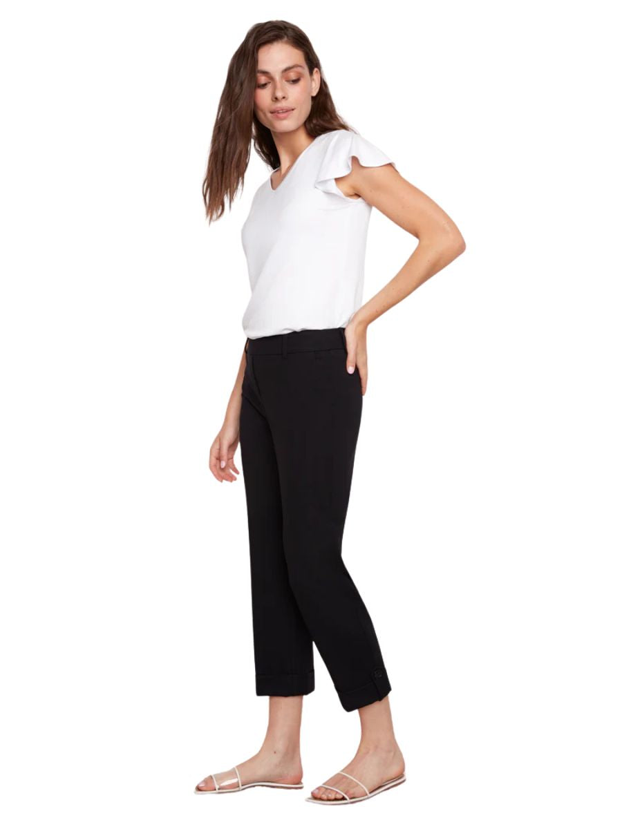 Slim black cropped pants paired with a white short-sleeve top and white strappy flat sandals on a model.