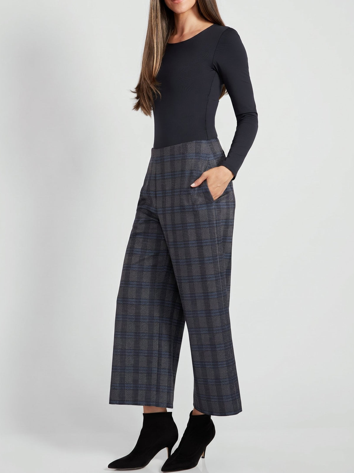 Black long-sleeve top paired with high-waisted wide-leg plaid trousers and black heeled ankle boots on a gray background.