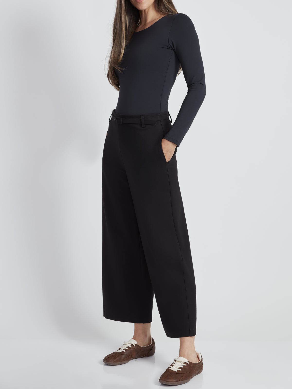 Black wide-leg pants paired with a fitted long-sleeve dark top and brown lace-up shoes on a light background.