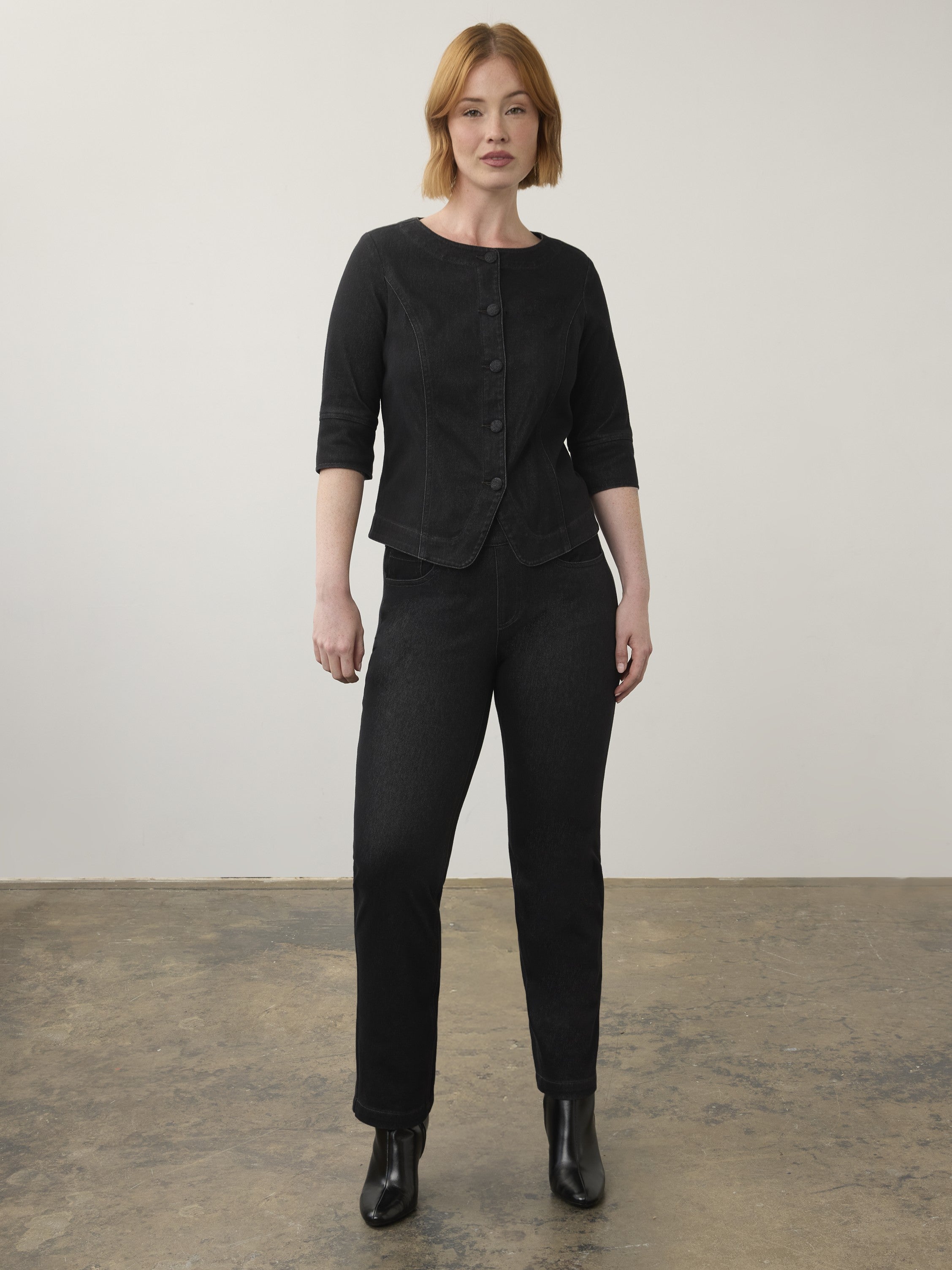 Black buttoned jacket with three-quarter sleeves paired with black denim jeans and black ankle boots.