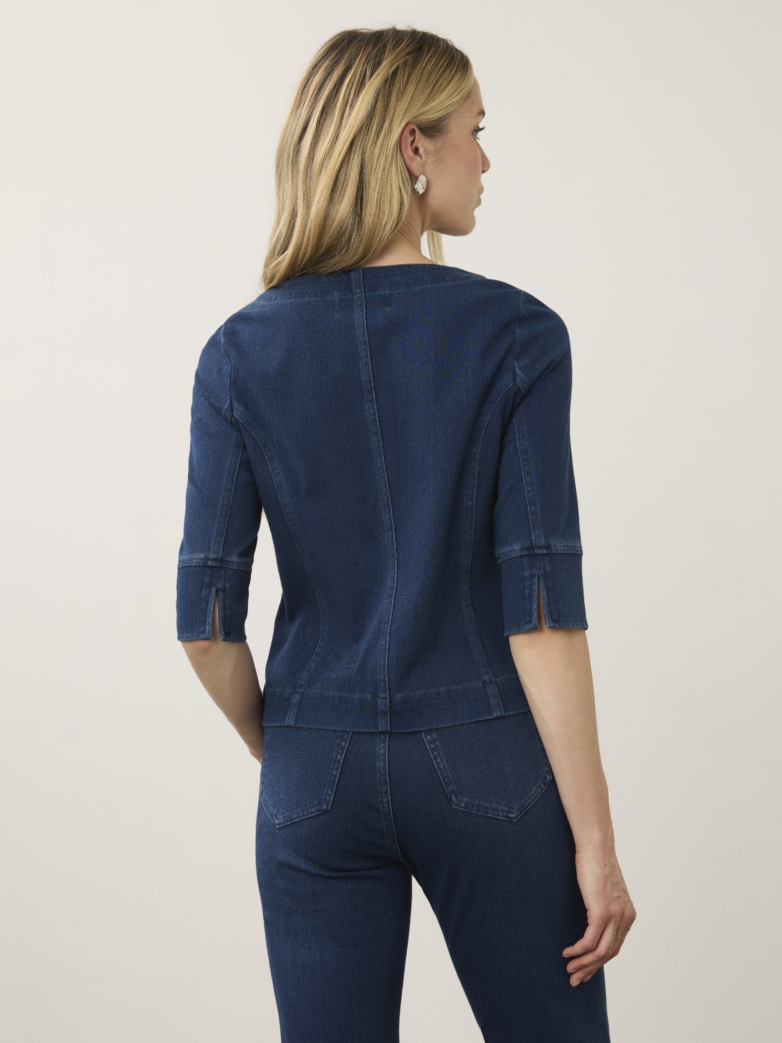 Back view of a dark denim jacket with three-quarter sleeves paired with matching denim jeans