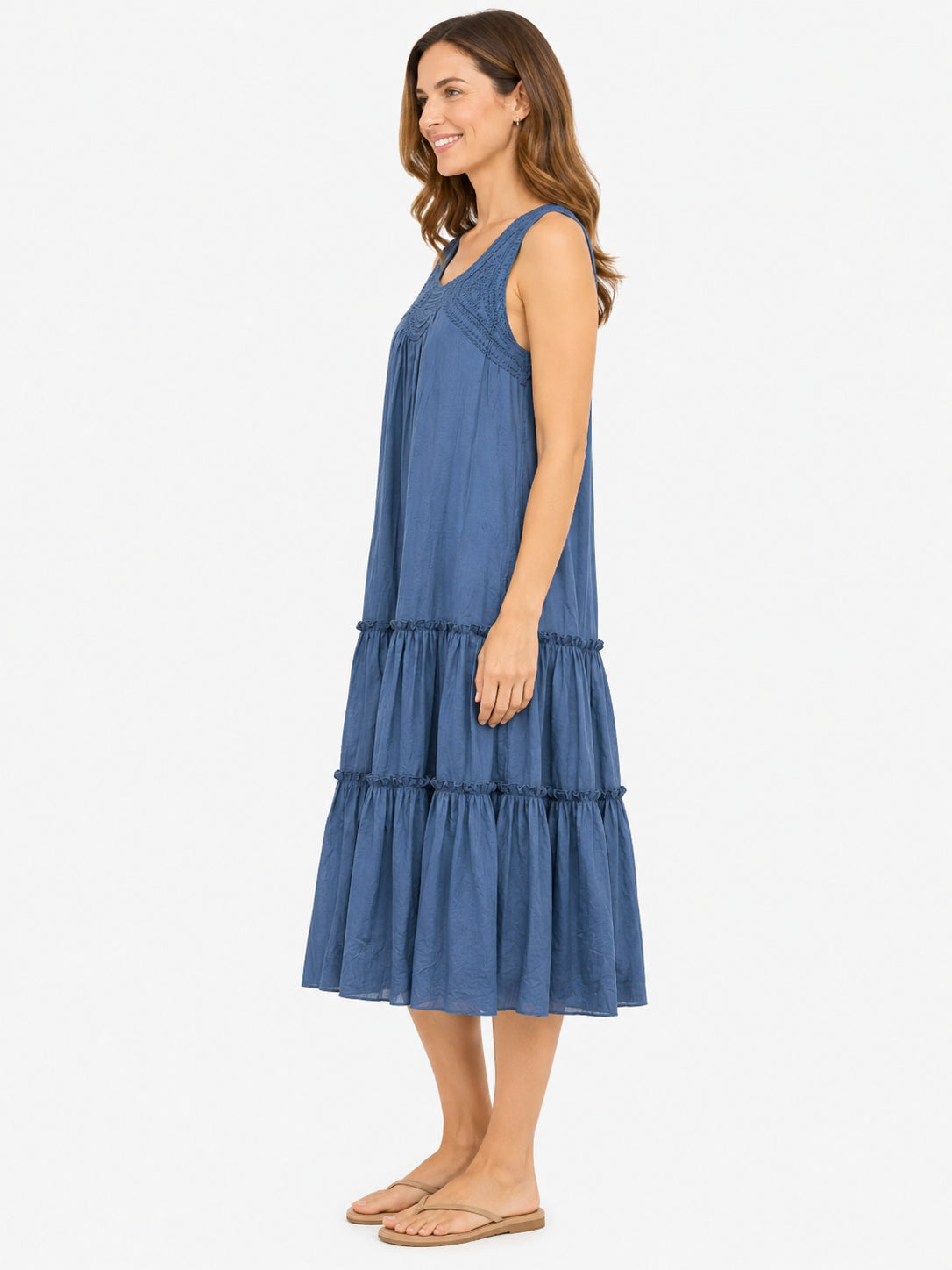 Sleeveless blue tiered midi dress with textured detailing on the bodice and relaxed fit paired with flat sandals.
