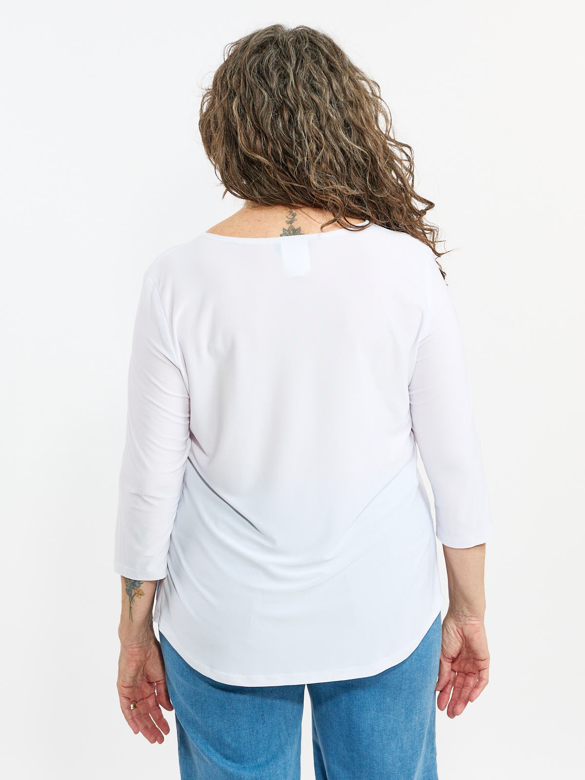 Back view of a white Elizabeth Scoop Neck 3/4 Sleeve Essential Top by Bali Corp. paired with blue jeans.