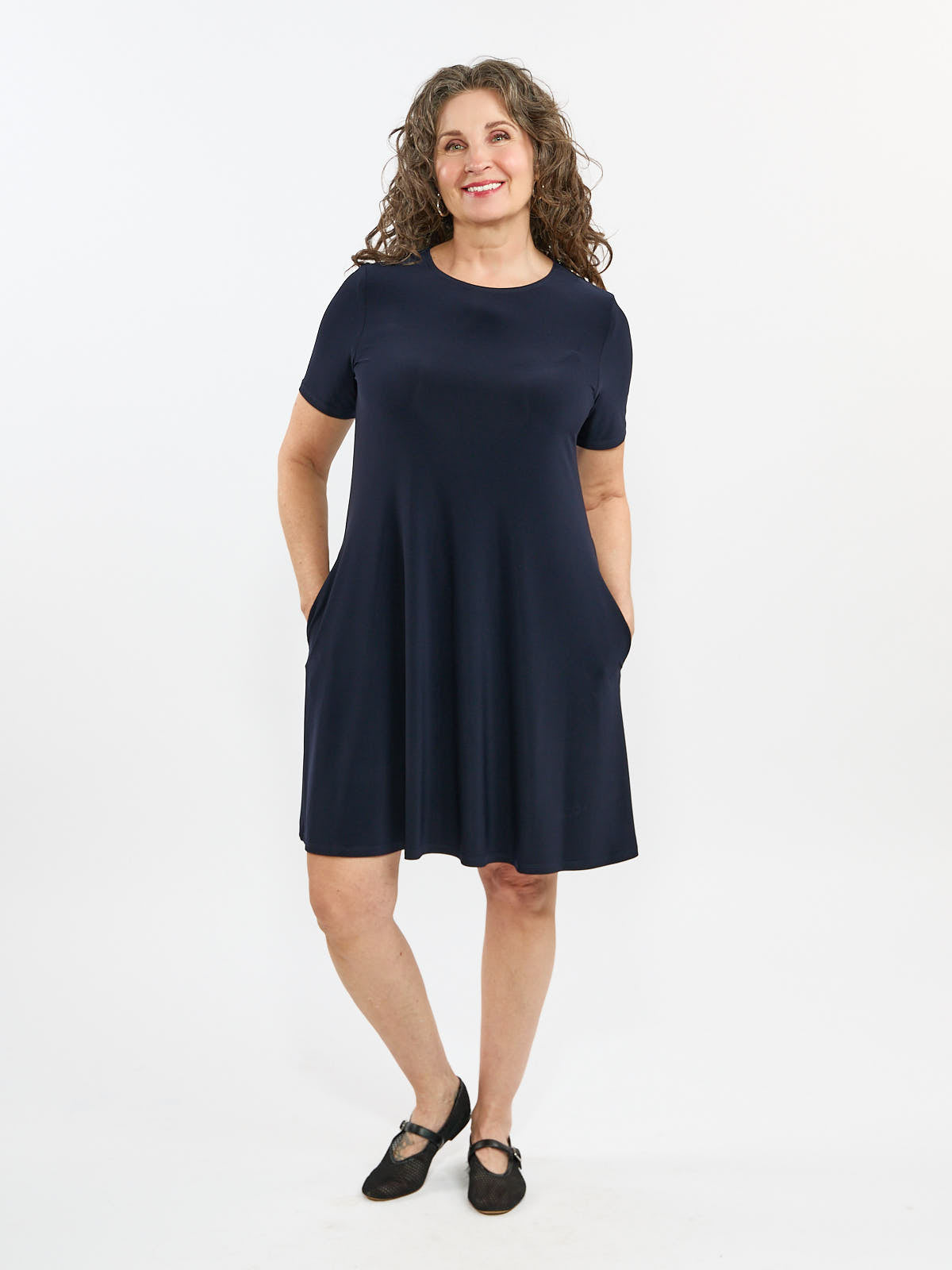 Short-sleeve navy blue casual dress with pockets and round neckline styled with black flat shoes.